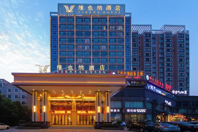 Un hotel con un letrero llamativo, varios pisos y una entrada bien iluminada.