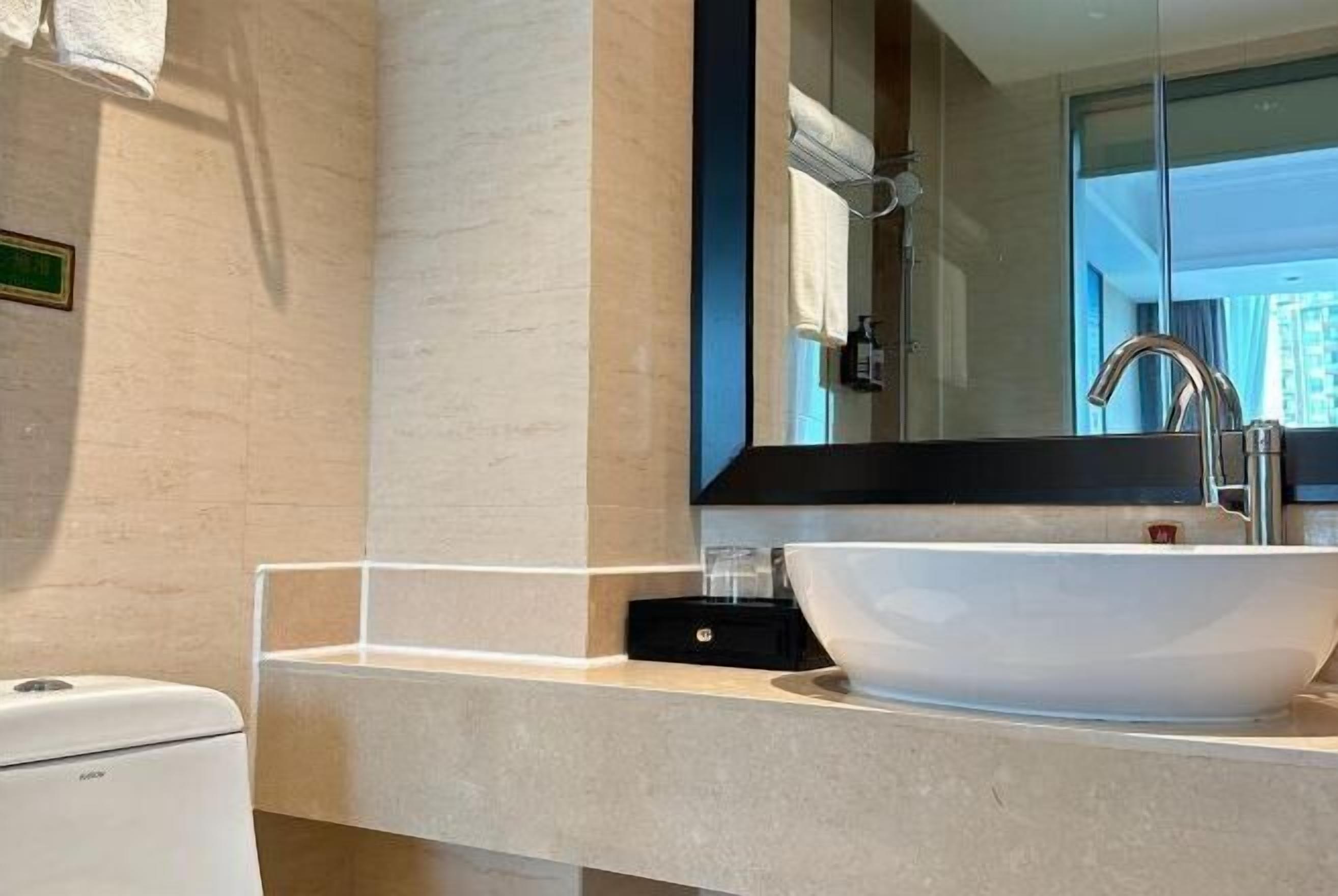 A modern bathroom with a large mirror, a white sink, and a handheld showerhead.