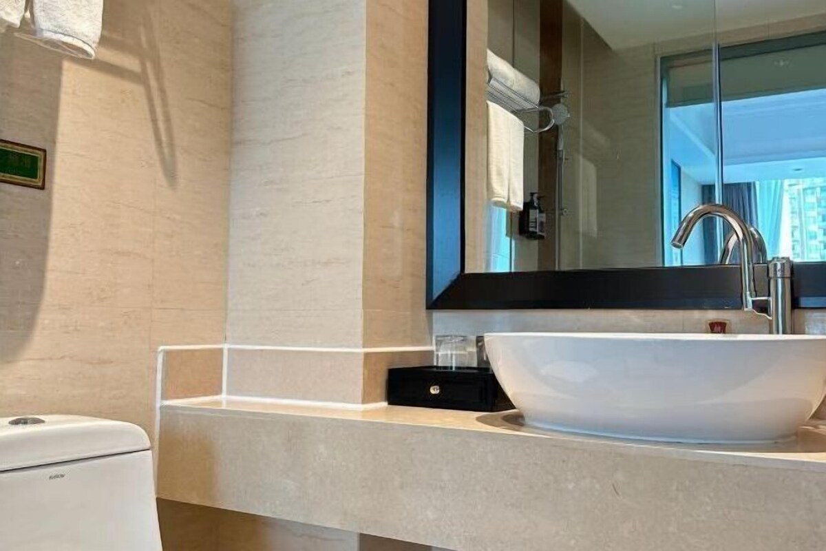 A modern bathroom with a large mirror, a white sink, and a handheld showerhead.