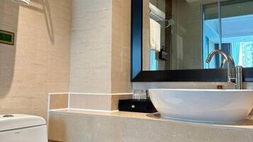A modern bathroom with a large mirror, a white sink, and a handheld showerhead.