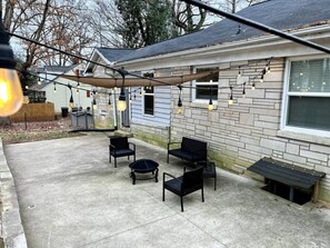 Un patio con muebles de exterior y luces colgantes.