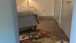 A bedroom with a bed, a nightstand, a lamp, and a patterned rug. - Enjoy Seattle with comfort and style! (Seattle)