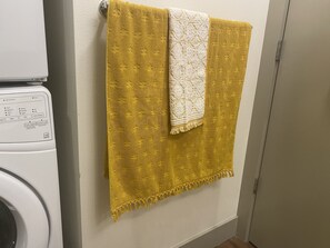 A washing machine with a control panel and towels hanging on a wall.