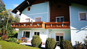 Un bâtiment à deux étages doté d’un balcon, de panneaux solaires et d’un jardin.