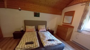 Un lit double avec une literie à motifs, une table de chevet, une commode et un miroir au mur.