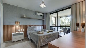 A modern hotel room with a bed, bedside table, and a view of the outdoors. - Completo Apart em Cumbuco por Carpediem (Caucaia)