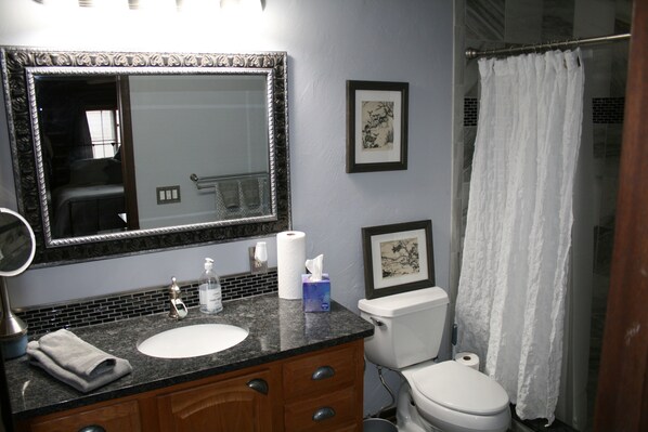 A bathroom with a sink, mirror, toilet, and shower curtain.