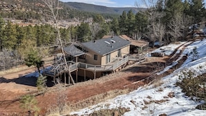 Una casa de dos pisos con un balcón, rodeada de un paisaje nevado y árboles.