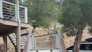 Una escalera de madera con un cartel que dice 'Welcome' en la parte inferior, que conduce a una zona cubierta con barandilla de metal.