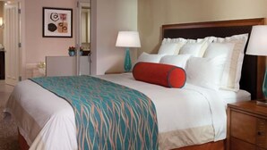 Een hotelkamer met een bed, nachtkastjes, een lamp en een deur.