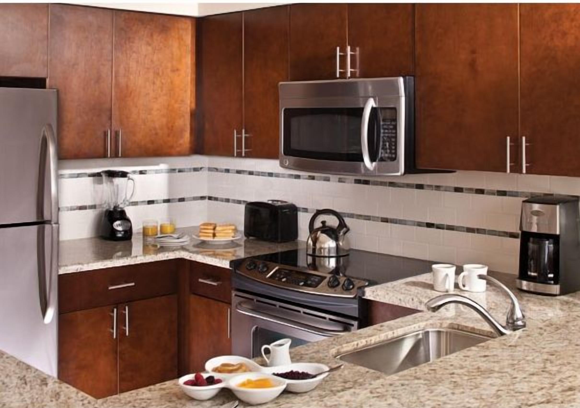 A kitchen with dark wooden cabinets, stainless steel appliances, and a granite countertop.