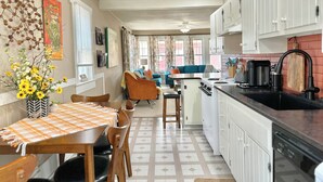 A kitchen with white cabinets, a black countertop, and a dining area with a table and chairs.