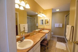 Une salle de bain avec deux lavabos, une douche et des toilettes.