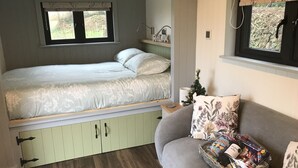 A cozy room with a bed, a sofa, and a small Christmas tree. - Wyncliffe Hideaway (Haverfordwest)