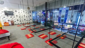 A modern hotel room with a large window, a flat-screen TV, and a red bean bag chair. - Oasis Capsules - Hostel (Siem Reap)