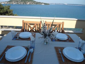 Une table dressée pour quatre personnes, avec la mer en toile de fond.