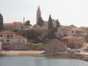 Une ville côtière caractérisée par un clocher d’église imposant, des bâtiments en pierre et une promenade au bord de l’eau paisible.
