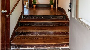 A wooden staircase with a handrail leading to a landing with a door and a light fixture above. - Mountain Views Newly Renovated Home (Ogden)