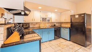 A modern kitchen with blue cabinets, a black refrigerator, and a built-in oven. - Mountain Views Newly Renovated Home (Ogden)