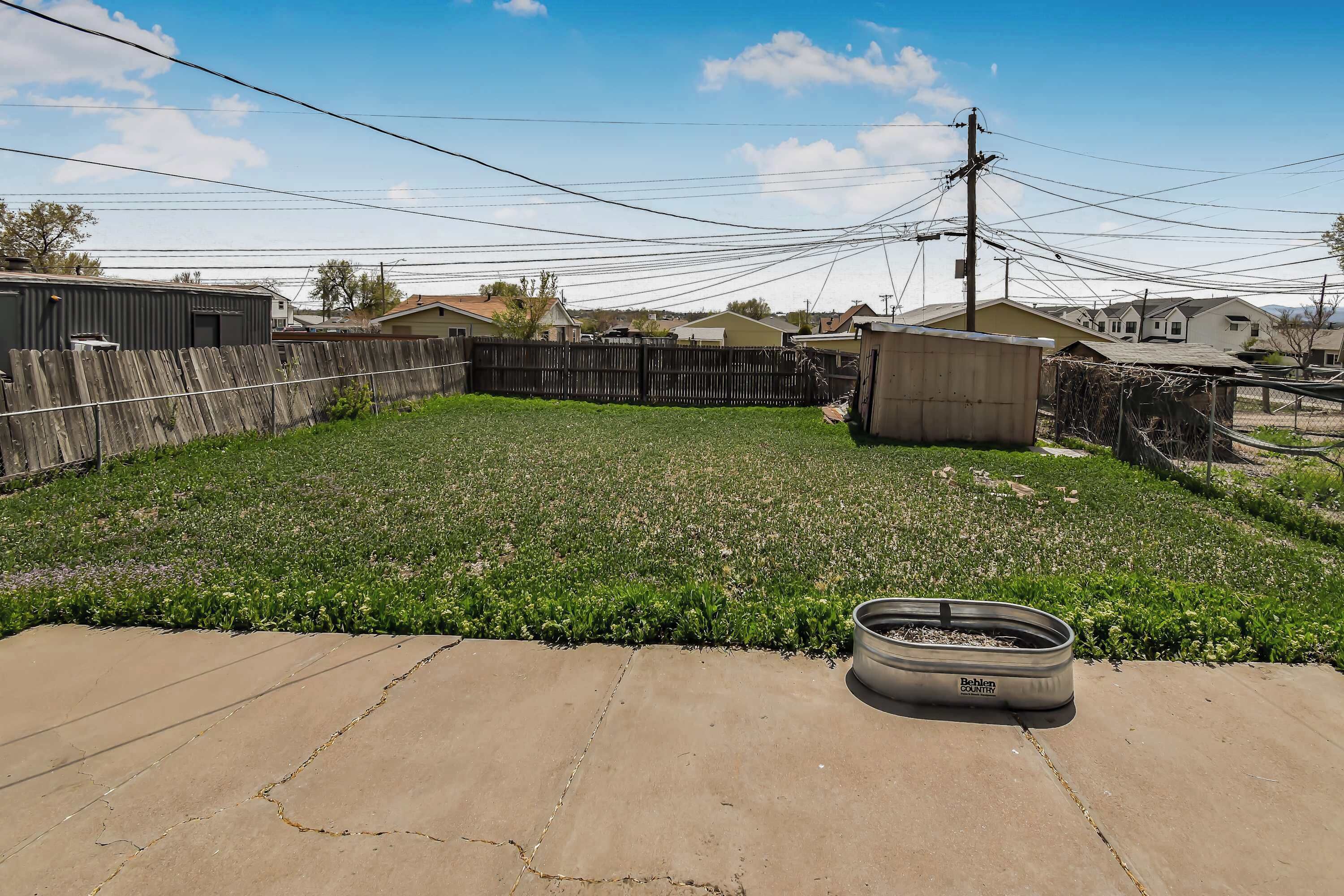 A backyard with a concrete patio, a small garden, and a metal container.