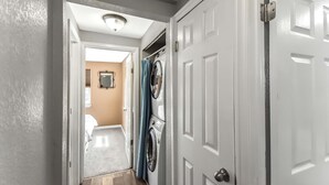 A hallway with a laundry area, a white door, and a ceiling light. - Dog Friendly and Family Sized Home (Denver)