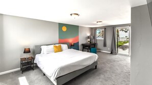 A modern hotel room with a large bed, a nightstand with a lamp, a small table with a lamp, and a view of the outside through a glass door. - Dog Friendly and Family Sized Home (Denver)
