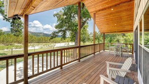 A wooden deck with a view of a grassy area and trees.