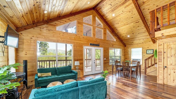 A spacious wooden cabin with a large living area, a dining table, and a staircase.