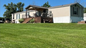 A single-story mobile home with a front porch, a small deck, and a well-maintained lawn. -  Lake Rathbun Get Away  (Rathbun)