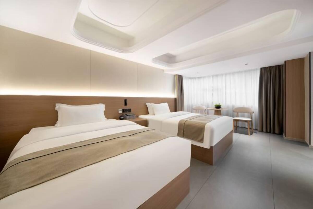 Ein modernes Hotelzimmer mit zwei Betten, einem Schreibtisch und einem Stuhl.