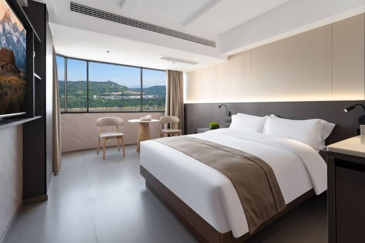 Ein modernes Hotelzimmer mit einem großen Bett, einem Schreibtisch und Blick auf die Landschaft.