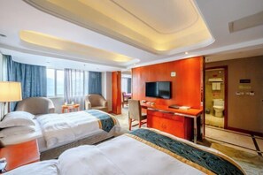 A hotel room with two beds, a desk, a TV, and a bathroom visible through an open door. - Xiang Shan Hotel (Zhong County)