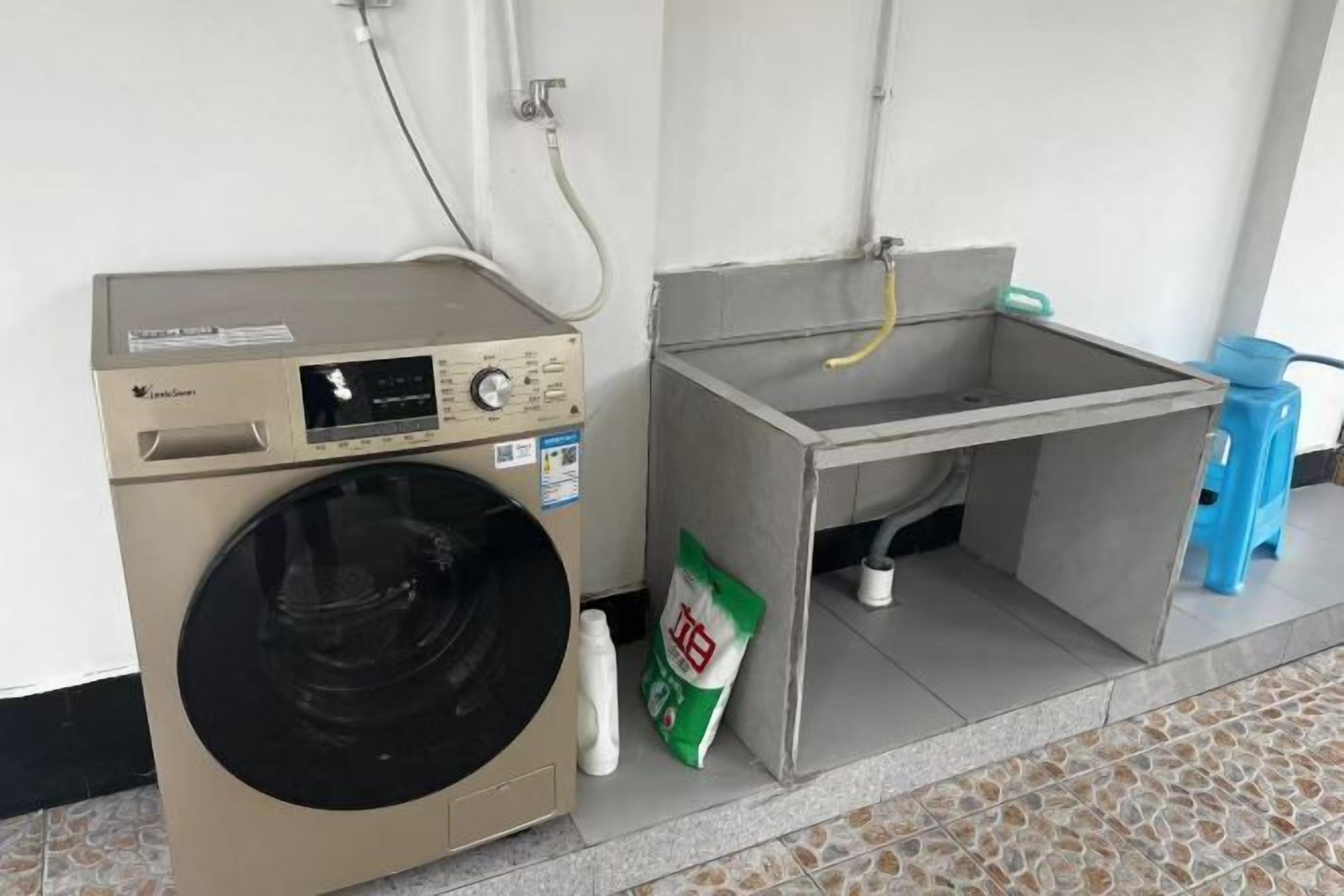 A compact laundry area with a washing machine, a sink, and a bag of detergent.