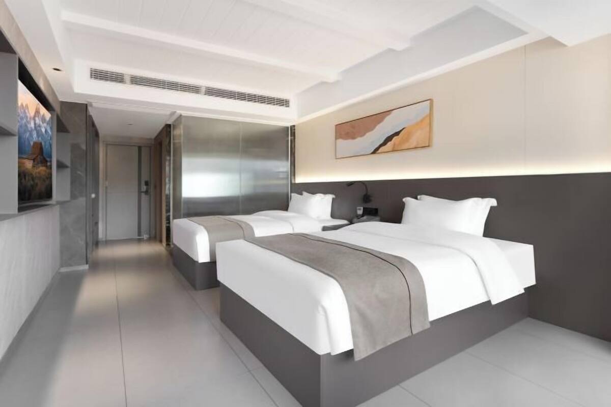 Ein modernes Hotelzimmer mit zwei Betten, einem großen Gem älde und Bergblick.