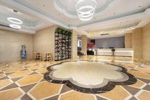 A hotel lobby with a patterned floor, a reception desk, and a seating area with chairs. - Xiang Shan Hotel (Zhong County)