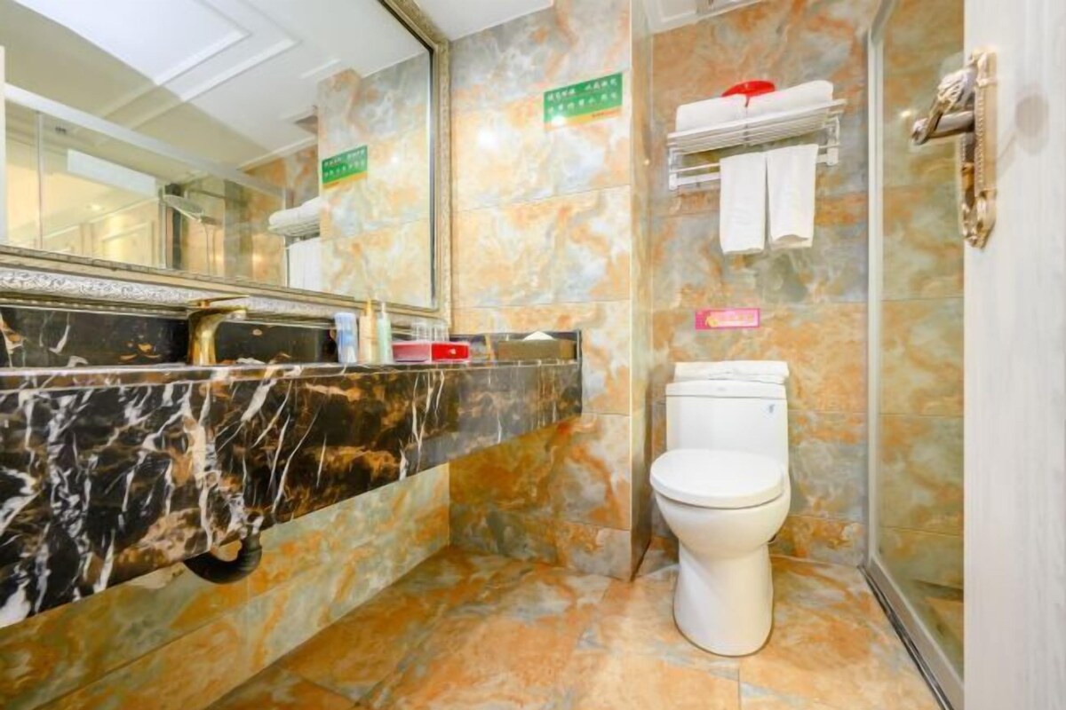 A bathroom with a marble vanity, a toilet, and a shower area.