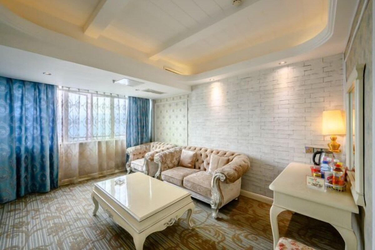 A living room with a tufted sofa, a white coffee table, and a small white side table with a lamp.