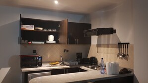 Uma cozinha moderna com armários escuros, micro-ondas embutido, fogão a gás e máquina de café.