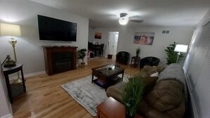 A living room with a flat-screen TV, a fireplace, a coffee table, and a sofa.