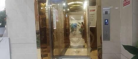 An entrance with a glass door, a no-smoking sign, and an elevator.