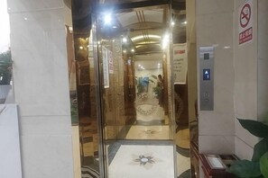 An entrance with a glass door, a no-smoking sign, and an elevator. - Q+ Treasure Palace Hotel (Shicheng)
