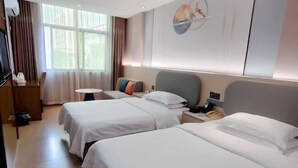 Quarto de hotel com duas camas, uma escrivaninha, uma cadeira, uma televisão e uma janela com cortinas.