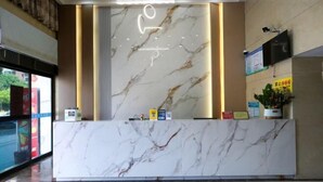 Uma receção de mármore com uma luminária vertical, uma televisão na parede e uma janela com vista para o exterior.