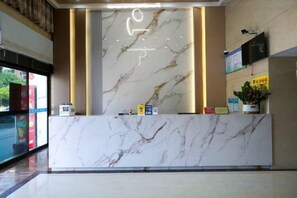 A reception desk with a marble top, a vertical light feature, and a potted plant. - Q+ Treasure Palace Hotel (Shicheng)
