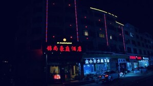 A building with illuminated signage, including a prominent red sign and a blue storefront. - Jinshang Haoting Hotel (Wuyi)