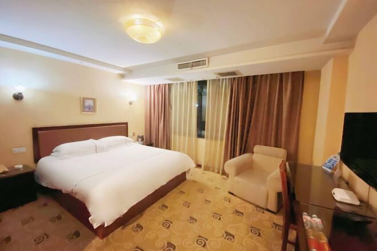 A hotel room with a bed, a chair, a desk, and a television.