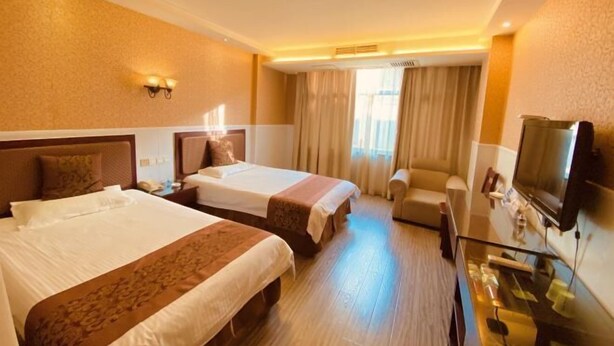 A hotel room with two beds, a sofa, a TV, and a desk with a computer. - Jinshang Haoting Hotel (Wuyi)