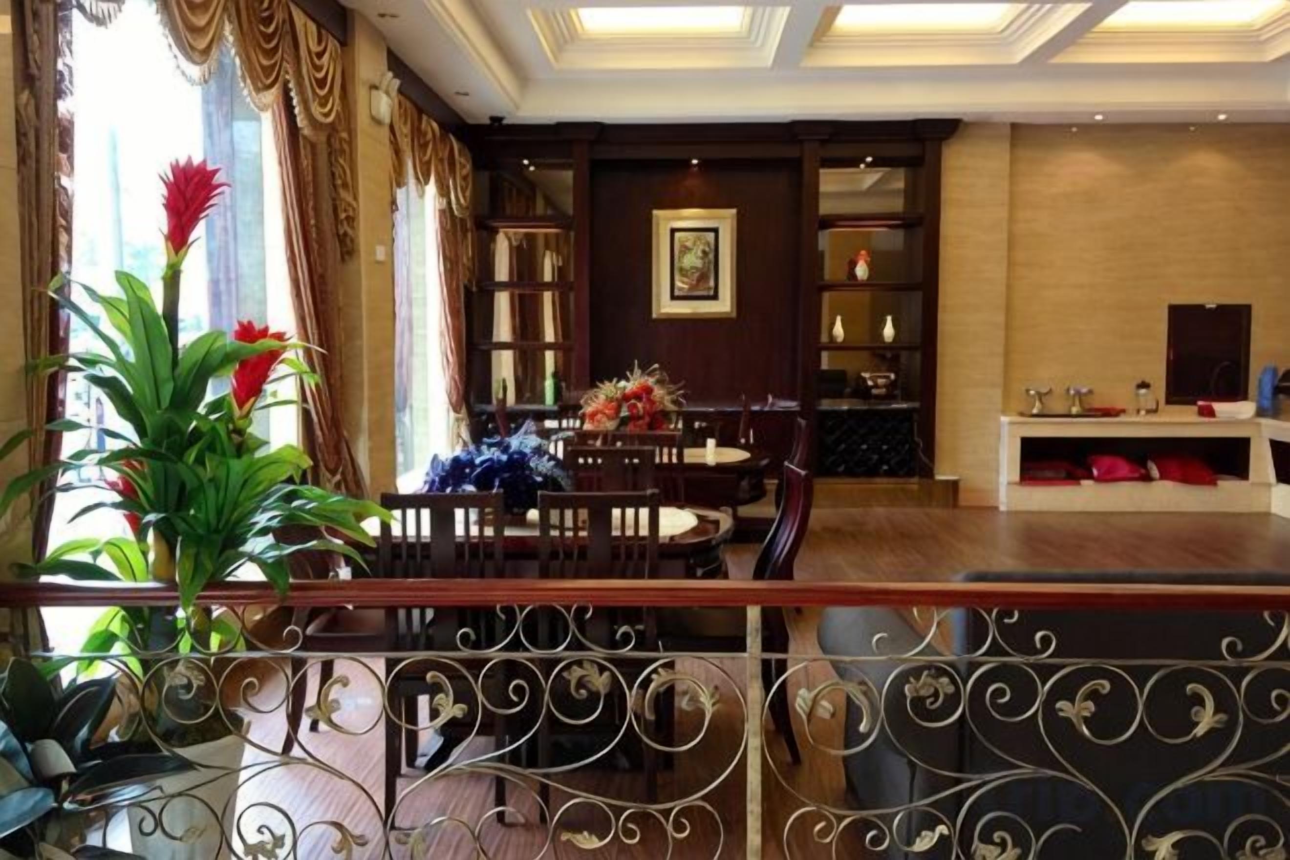 Um saguão de hotel com área de refeições, balcão de recepção e uma estante de livros.