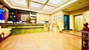 A hotel lobby with a reception desk, a staircase, and a wooden floor. - Jinshang Haoting Hotel (Wuyi)
