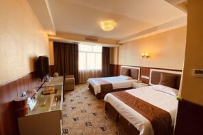 A hotel room with two beds, a desk with a chair, a television, and a window with curtains.